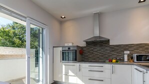 Een moderne keuken met een inbouwoven, magnetron en een spatwand van steen.