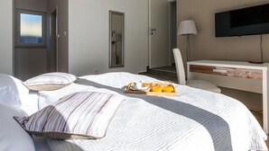 Een hotelkamer met een bed, bureau, televisie en raam.