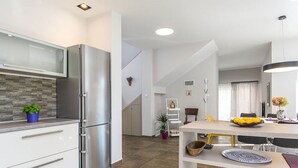 Een moderne keuken met een roestvrijstalen koelkast, witte kasten en een backsplash met een herringbone-patroon.
