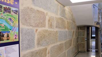 A hallway with a stone wall and a poster on the left.