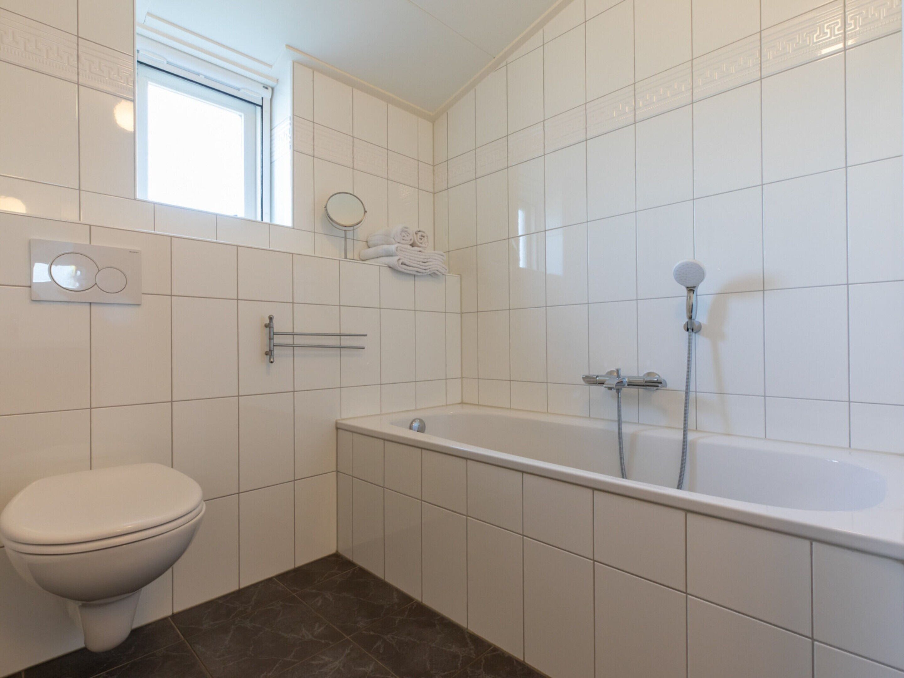 Ein Badezimmer mit Toilette, Badewanne und Dusche.