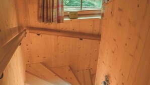 A wooden staircase with a handrail, leading to a window with plaid curtains. - Saerbecker Berghutte (Heiligenblut)