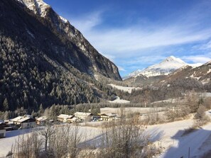 A mountainous landscape with snow-covered peaks, a valley with sparse buildings, and a clear sky. - Saerbecker Berghutte (Heiligenblut)