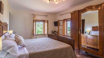 A bedroom with a large bed, a wooden wardrobe, and a chandelier.