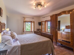 A bedroom with a large bed, a wooden wardrobe, and a chandelier.