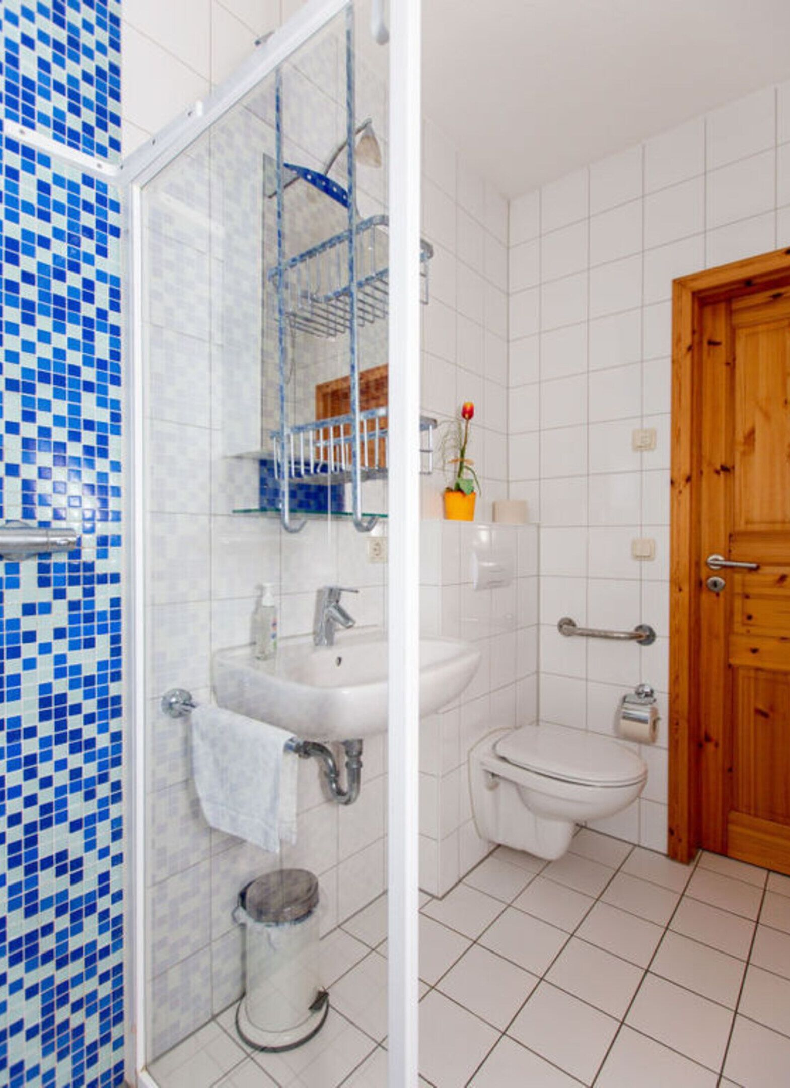 Un baño con ducha, lavabo, inodoro y puerta de madera.