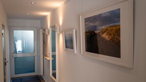 A hallway with a door, a bench, and framed pictures on the wall. - Moi"n Dag Modern Retreat (Borkum)