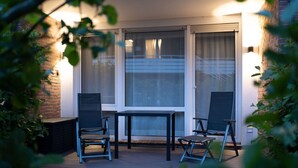 An outdoor patio with a table and two chairs, surrounded by a brick wall and large windows. - Moi"n Dag Modern Retreat (Borkum)