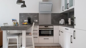 A modern kitchen with white cabinetry, a built-in oven, and a grey countertop. - Moi"n Dag Modern Retreat (Borkum)