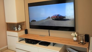 Un téléviseur à écran plat fixé au mur, avec un meuble de rangement en bois placé en dessous.