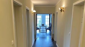 Un couloir doté d’un plancher en bois, de murs blancs et d’un coin repas situé au fond.
