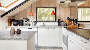 Une cuisine moderne avec des meubles blancs, une grande fenêtre et un puits de lumière.