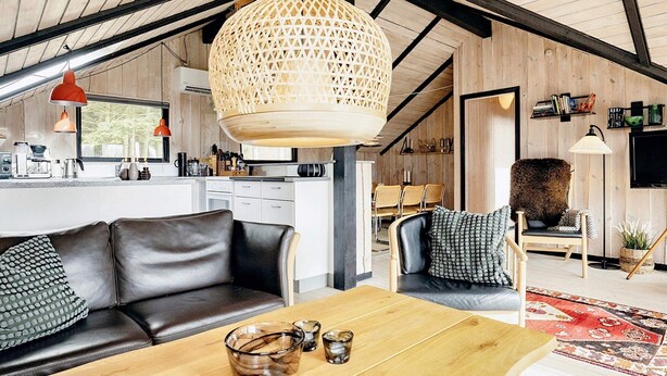 Un salon moderne avec une table en bois, un canapé en cuir et un grand luminaire tressé.