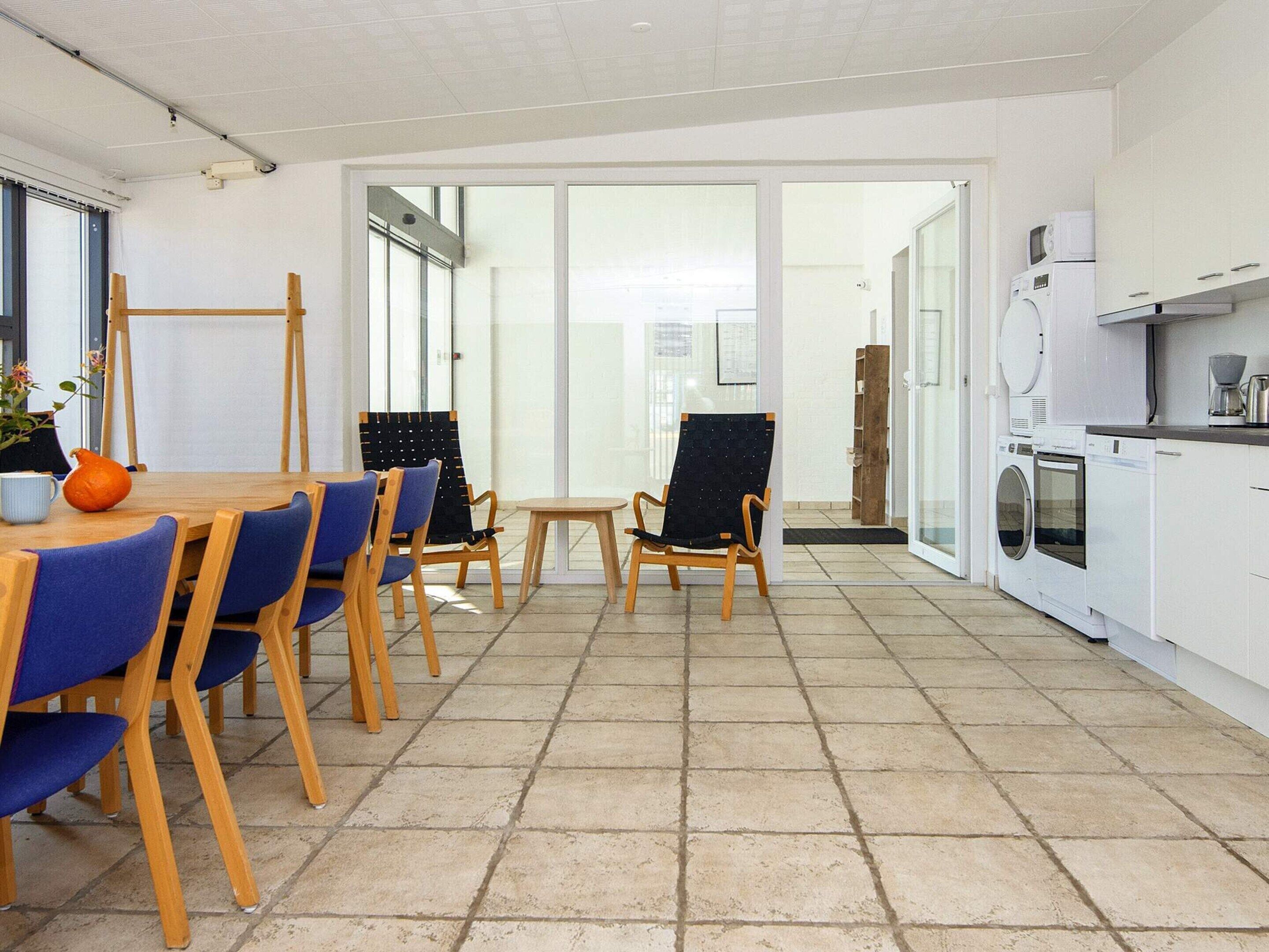 Una cocina moderna con zona de comedor, que incluye una mesa con sillas, una cafetera y una lavadora.
