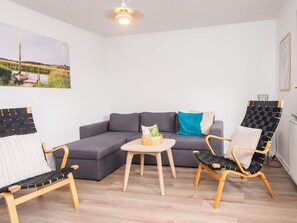 A room with a grey sofa, two armchairs, a small round table, and a ceiling light fixture. - 4 Person Holiday Park Home in Ulfborg (Ulfborg)