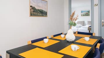 A hotel room with a dining table, chairs, a bed, and a door marked with the number 14.