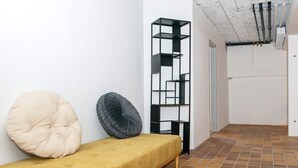A minimalist room with a sofa, two cushions, and a black shelving unit against a white wall. - 4 Person Holiday Park Home in Ulfborg (Ulfborg)