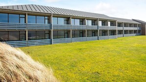 A modern building with a flat roof, large windows, and a grassy area in front. - 4 Person Holiday Park Home in Ulfborg (Ulfborg)