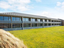 A modern building with a flat roof, large windows, and a grassy area in front.