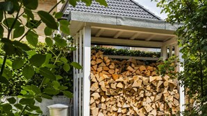 A covered outdoor area with a stack of firewood. - Fischer Heiligenhafen 4b (Heiligenhafen)