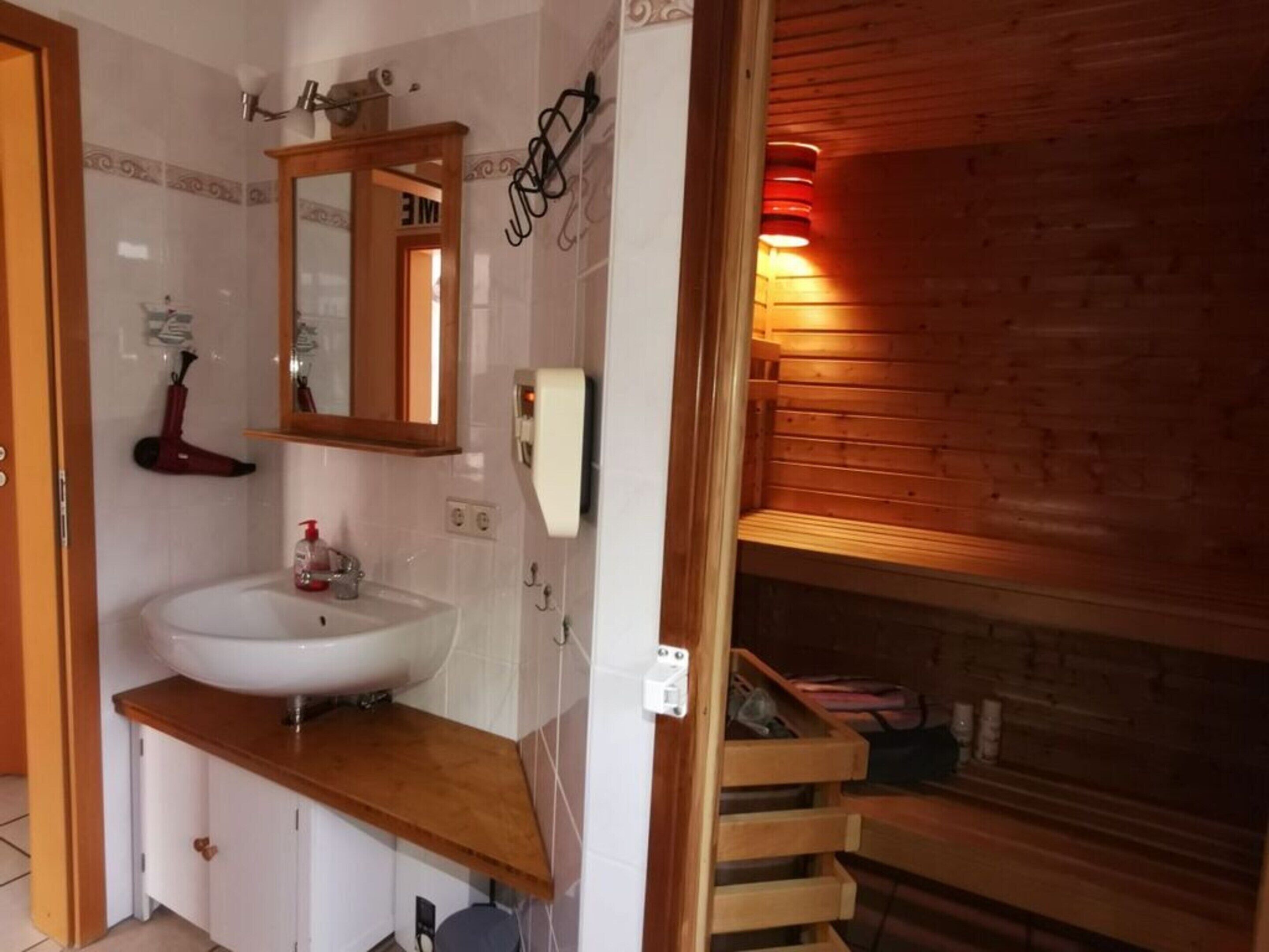 A bathroom with a wooden vanity, a sink, a mirror, and a towel rack.
