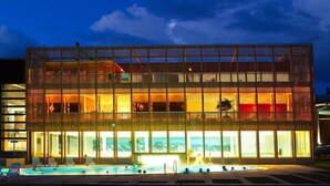 Un hotel moderno con piscina, varios balcones y vistas a las montañas.