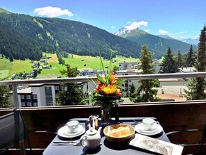 A table set for breakfast with a mountain view, a vase with flowers, and a postcard. - - Fantastisch Bergpanorama (Davos)