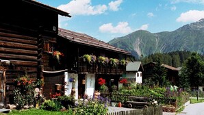 Un edificio de madera rústico con balcones decorados con flores, frente a un paisaje montañoso.