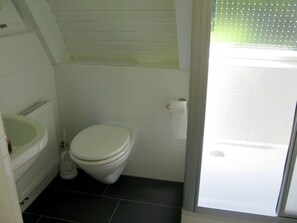 A bathroom with a toilet, a sink, and a shower area. - Modern Apartment Near Centre (Leinsweiler)