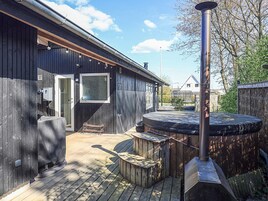 En træterrasse med jacuzzi, overdækket siddeområde og sauna.