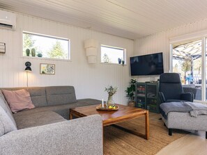 A cozy living room with a sofa, armchair, coffee table, and a flat-screen TV.