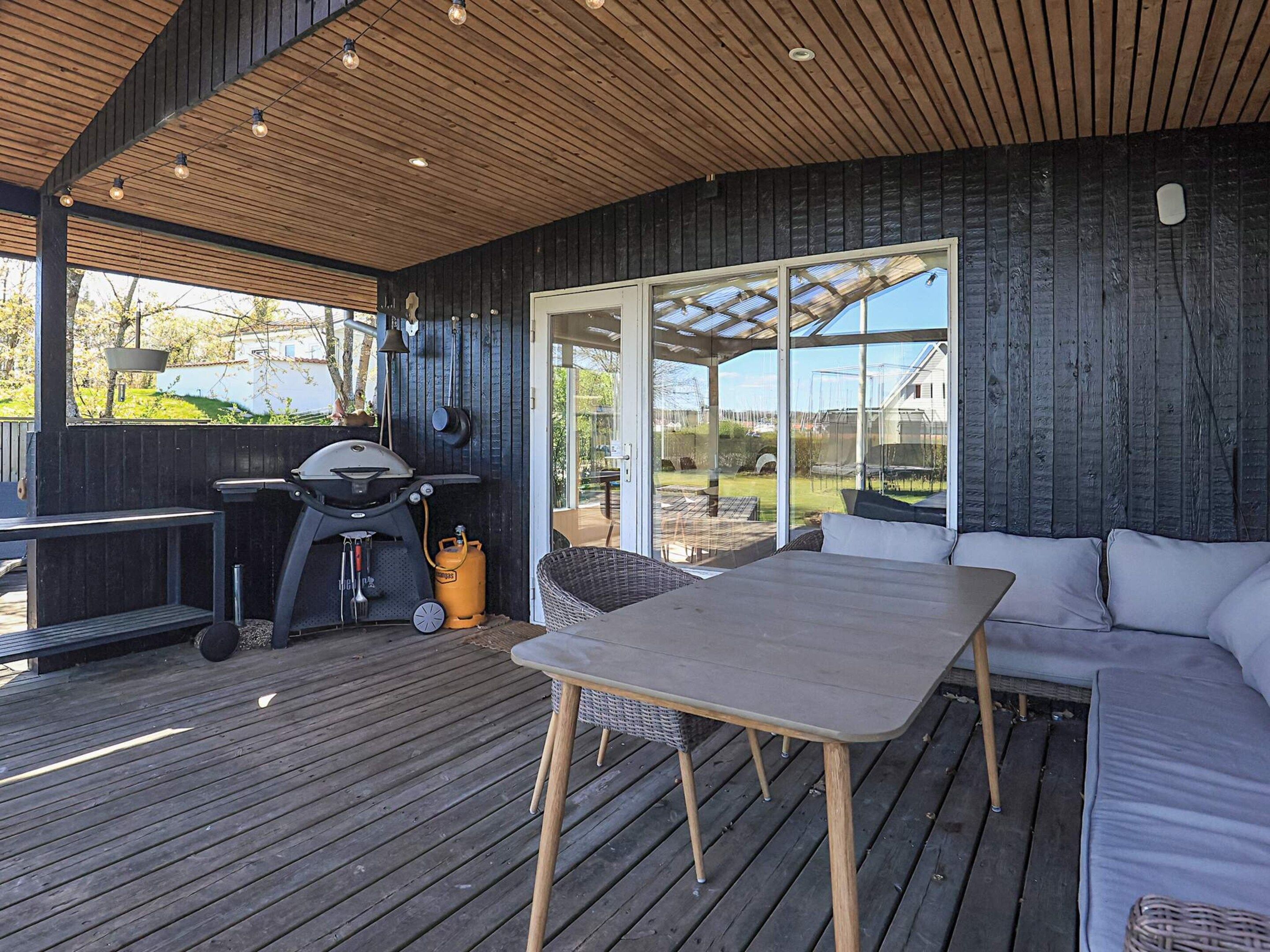 Una terraza al aire libre con una parrilla, zona de estar y vistas al jardín trasero.
