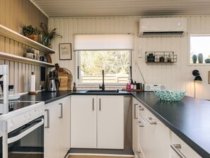 Una cocina moderna con armarios blancos, encimera negra y ventana con vista a zonas verdes.