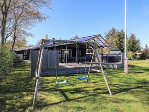 A wooden deck with a swing set and a covered seating area.