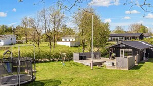 A residential property with a trampoline, a swing set, and a deck area. - 6 Person Holiday Home in Hojslev (Hojslev)