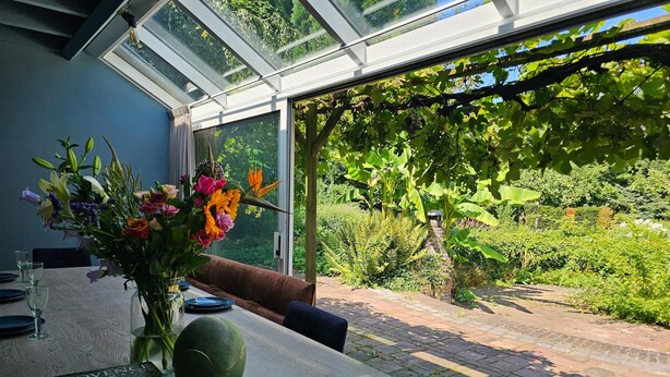 Un coin repas avec une table dressée pour deux personnes, un vase de fleurs et un livre intitulé « Provence ».