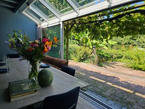 A dining area with a table set for two, a vase of flowers, and a book titled "Provence". - Holiday Home in Leende for ten Person (Leende)