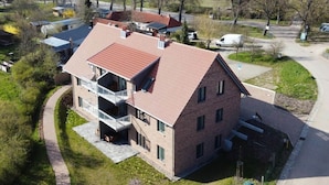 Ein zweistöckiges Haus mit rotem Ziegeldach und einem Balkon im oberen Stockwerk, sowie einem gepflasterten Auffahrt.