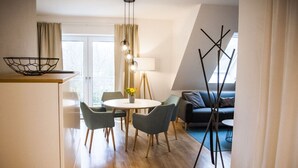 Ein modernes Wohnzimmer mit einer Couch, einem Esstisch mit Stühlen, einer Stehlampe und einer Bodlampe.