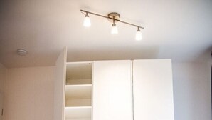 Ein Zimmer mit einem weißen Kleiderschrank, einem blauen Sessel und Holzboden.