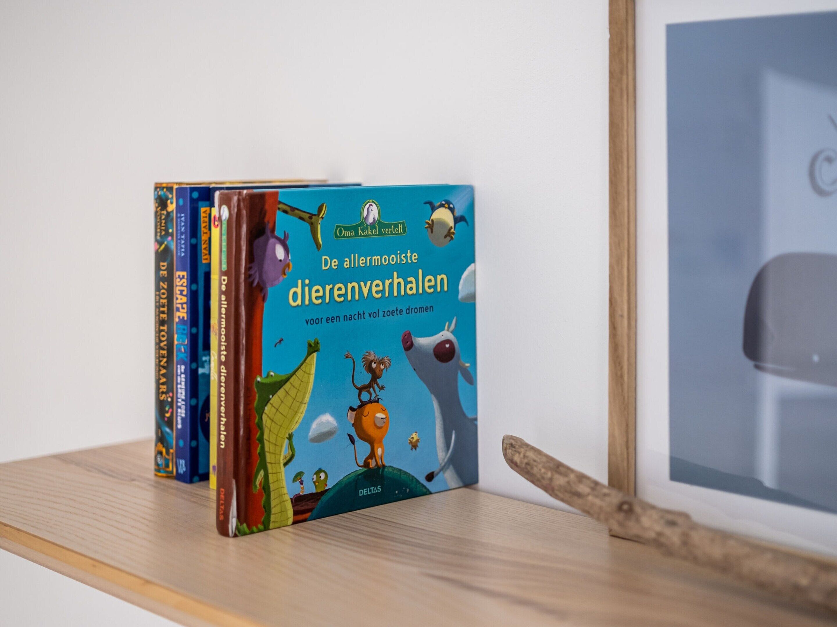 A stack of children's books on a wooden shelf.