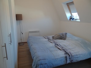 A bedroom with a bed, a bedside lamp, a radiator, and a window with a view. - Apartment in Nieuwpoort With Terrace (Nieuwpoort)