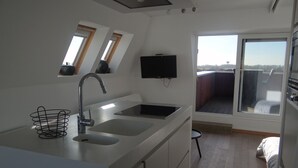 A modern kitchen with a large sink, a built-in stove, and a flat-screen TV mounted above the counter. - Apartment in Nieuwpoort With Terrace (Nieuwpoort)