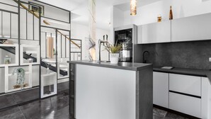 A modern kitchen with a central island, white cabinetry, and a dark countertop. - Villa in Istria With Heated Eco Pool (Brtonigla)