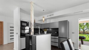 A modern kitchen with a central island, built-in appliances, and a view of the outdoors. - Villa in Istria With Heated Eco Pool (Brtonigla)