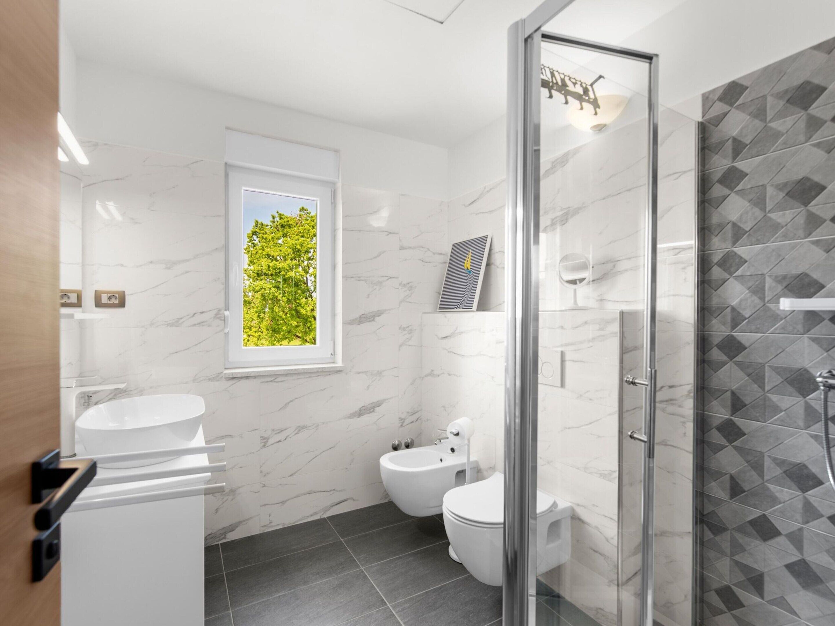 Une salle de bain moderne avec une douche à parois de verre, des toilettes et un lavabo.