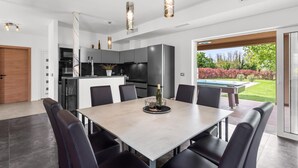 A modern kitchen with a dining area, a pool, and a view of the garden. - Villa in Istria With Heated Eco Pool (Brtonigla)