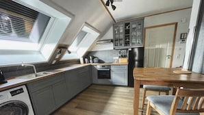 Une cuisine moderne dotée d’une verrière, d’appareils électroménagers intégrés et d’un coin repas avec une table et des chaises en bois.