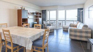 Amplia sala de estar con una mesa de comedor, sillas, un sofá y un balcón con vistas.