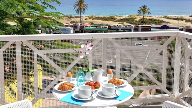 Una mesa de comedor con alimentos para el desayuno y vista a la playa y al océano.